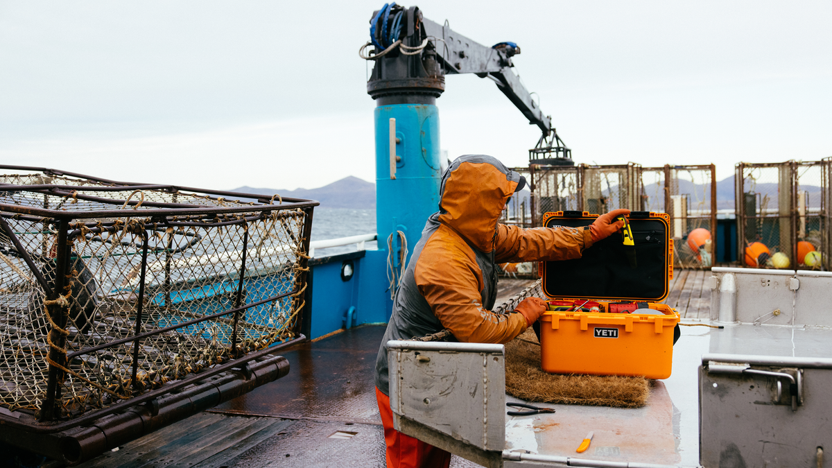 Fischer mit YETI Kühlbox in King Crab Orange auf einem Krabbenkutter